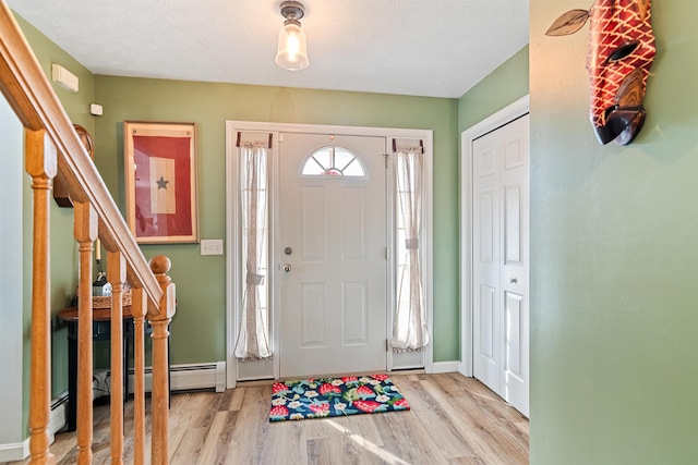 entryway featuring stairs, wood finished floors, baseboards, and a textured ceiling