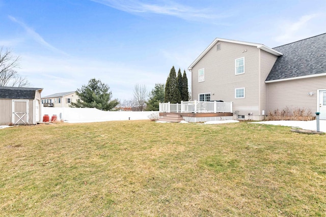 view of yard featuring a deck, an outbuilding, fence, and a shed