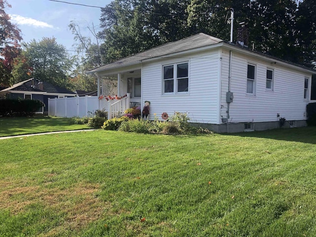 view of front of property with a chimney, covered porch, a front lawn, and fence