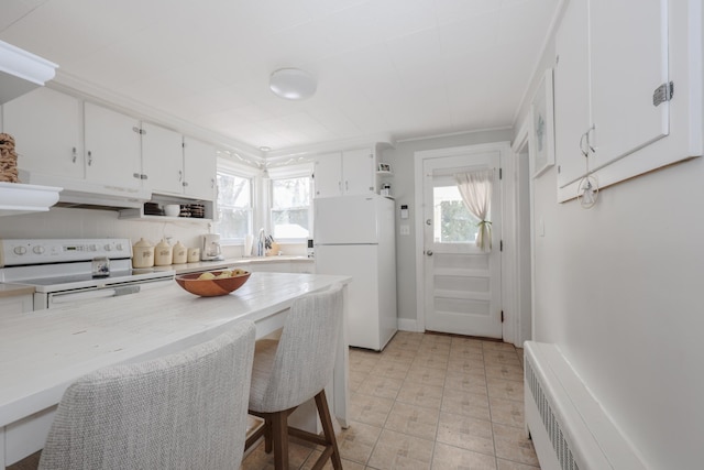 kitchen featuring white appliances, radiator, light countertops, white cabinets, and under cabinet range hood