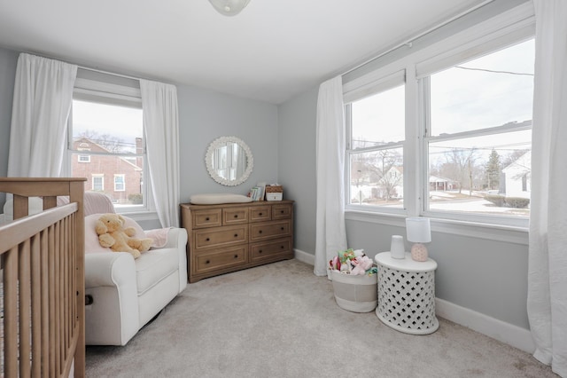 carpeted bedroom with a crib and baseboards