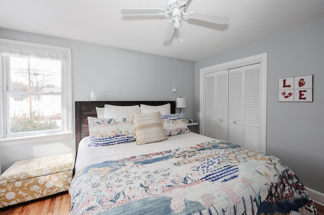 bedroom featuring ceiling fan, a closet, multiple windows, and wood finished floors