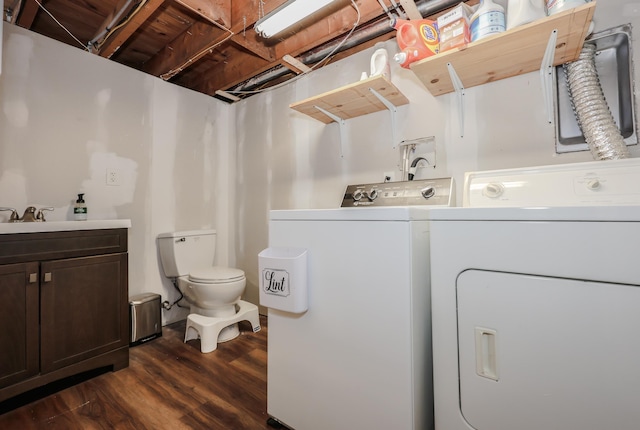 laundry area with dark wood finished floors, laundry area, washer and dryer, and a sink