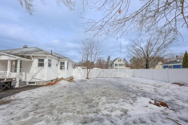 snowy yard with a gate and a fenced backyard