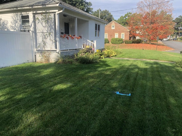 view of yard with covered porch and fence