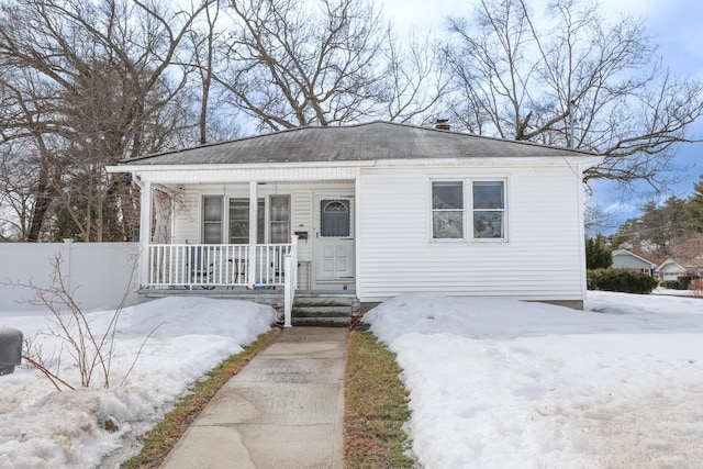 bungalow-style house featuring a porch, fence, and a shingled roof