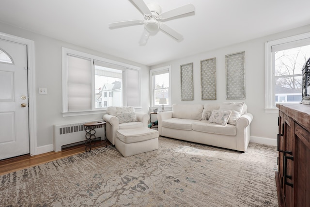 living area featuring baseboards, a ceiling fan, wood finished floors, and radiator heating unit