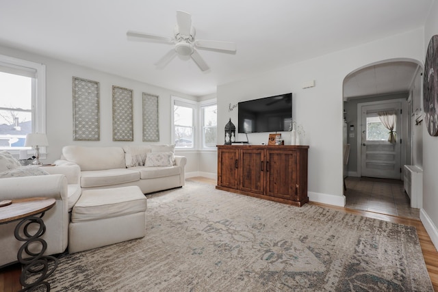 living room with arched walkways, radiator, a healthy amount of sunlight, and wood finished floors