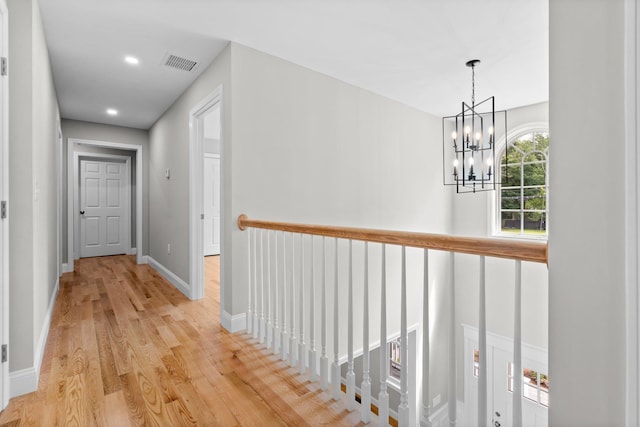 hall with light wood-type flooring, visible vents, recessed lighting, baseboards, and a chandelier