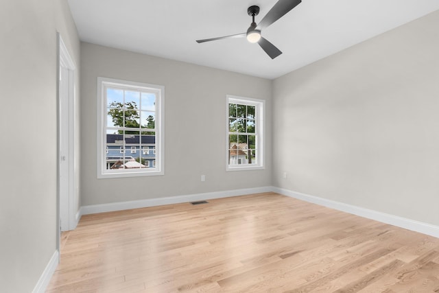 unfurnished room with a ceiling fan, light wood-style floors, visible vents, and baseboards