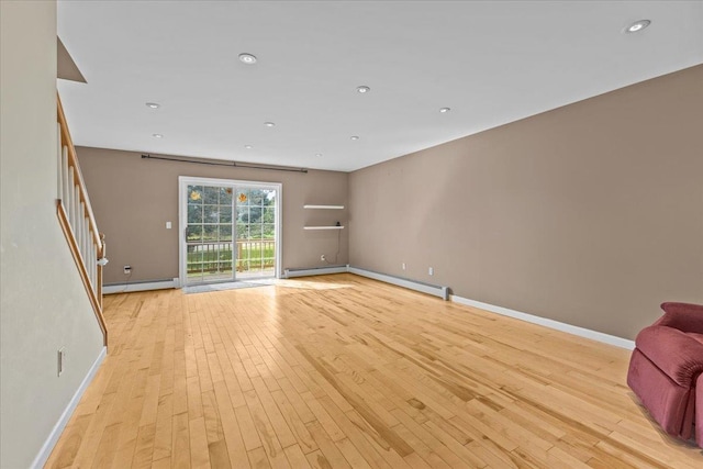 unfurnished living room with stairs, light wood-type flooring, baseboards, and a baseboard radiator