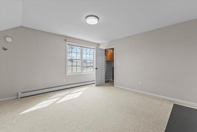 spare room featuring baseboard heating, light colored carpet, and baseboards