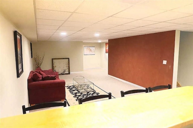 living room featuring light colored carpet, a paneled ceiling, and baseboards