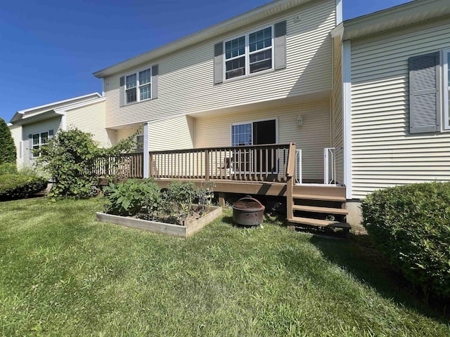 back of property with a lawn, a wooden deck, and a garden