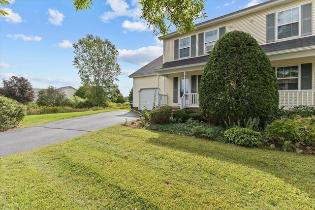 view of front of property with aphalt driveway, a garage, covered porch, and a front lawn