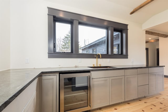 kitchen with gray cabinetry, beverage cooler, light wood-style floors, and a sink