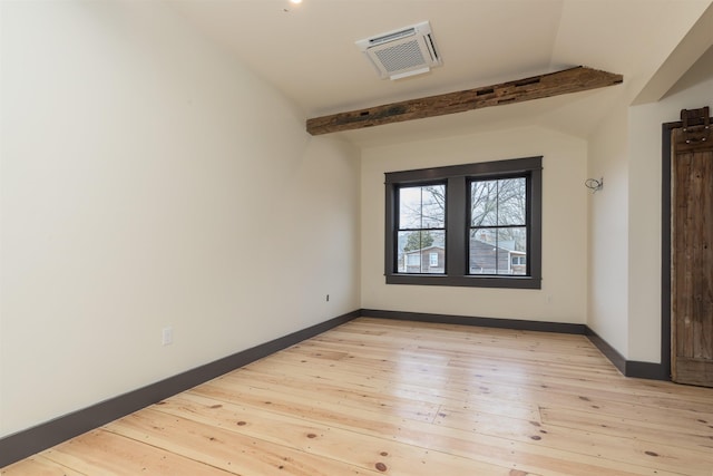 unfurnished room featuring vaulted ceiling with beams, light wood-style floors, visible vents, and baseboards