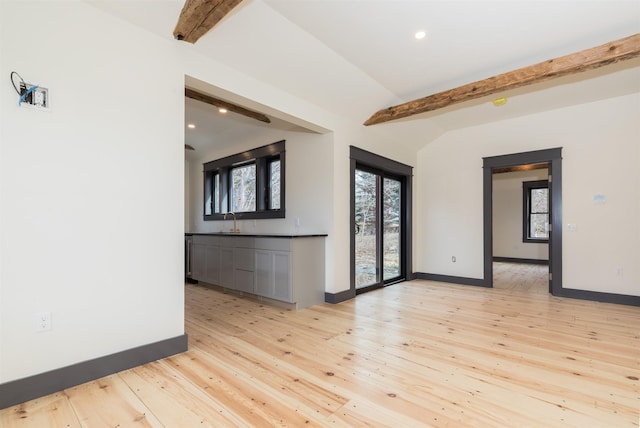 empty room with a healthy amount of sunlight, light wood-type flooring, baseboards, and a sink