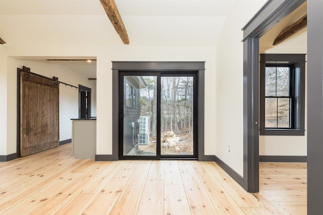 interior space with hardwood / wood-style floors, beam ceiling, plenty of natural light, and a barn door