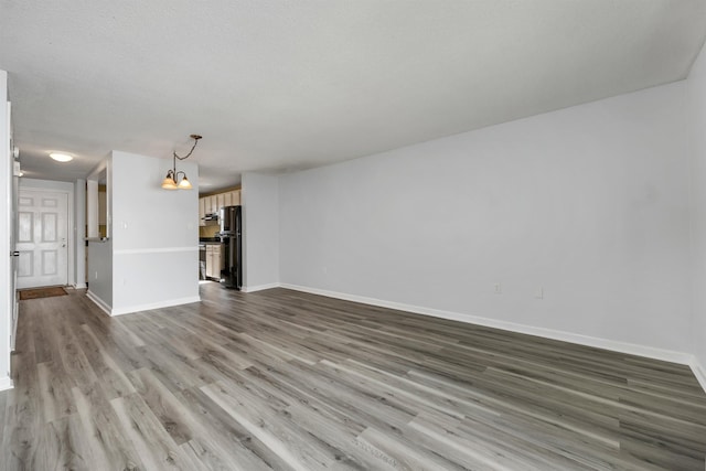 unfurnished living room featuring wood finished floors and baseboards