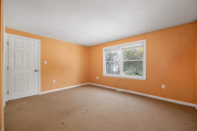 unfurnished room featuring carpet flooring, visible vents, a textured ceiling, and baseboards