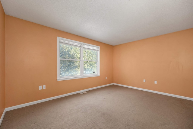 empty room featuring visible vents, a textured ceiling, baseboards, and carpet floors