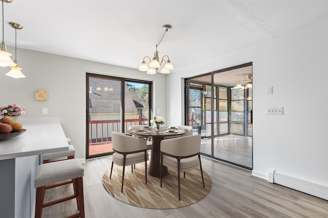 dining room with light wood-style flooring, a notable chandelier, baseboards, and a baseboard radiator