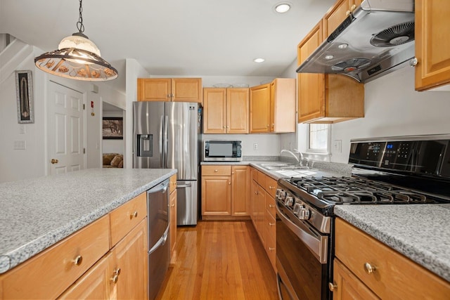 kitchen with light wood-style flooring, a sink, hanging light fixtures, extractor fan, and appliances with stainless steel finishes