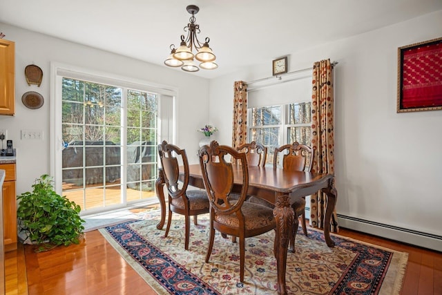 dining room featuring a healthy amount of sunlight, light wood-type flooring, and an inviting chandelier