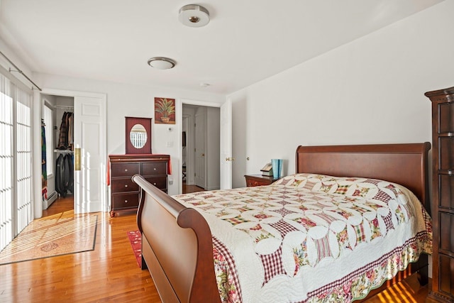 bedroom with a closet, light wood-style flooring, and a baseboard radiator