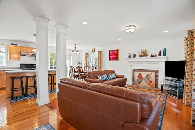 living area with ornate columns, recessed lighting, a healthy amount of sunlight, and light wood finished floors