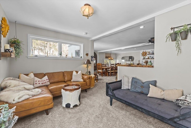 living room with beamed ceiling, carpet, and a ceiling fan