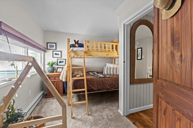 bedroom featuring arched walkways, baseboard heating, baseboards, and wood finished floors