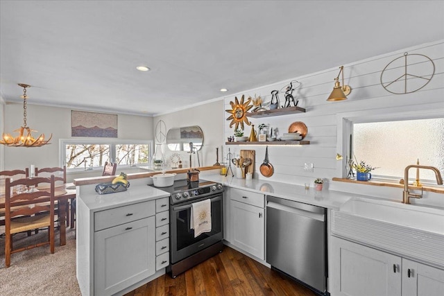 kitchen with a sink, light countertops, appliances with stainless steel finishes, a peninsula, and open shelves