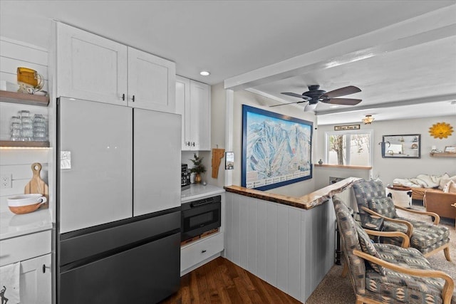 kitchen with dark wood-type flooring, ceiling fan, light countertops, freestanding refrigerator, and white cabinetry