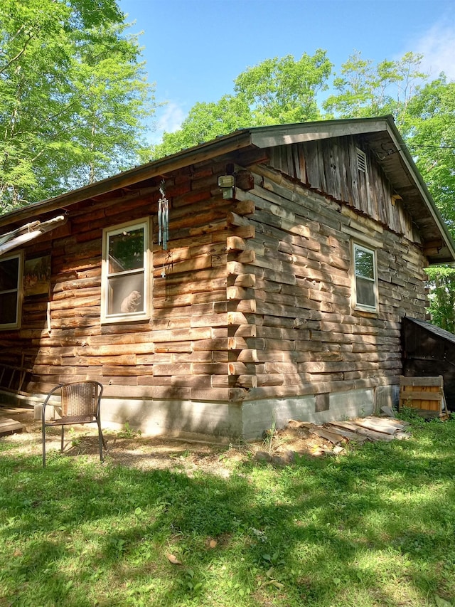 view of side of property featuring log siding and a yard