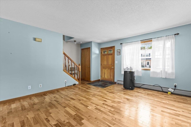 entrance foyer featuring baseboards, stairs, baseboard heating, wood finished floors, and a textured ceiling