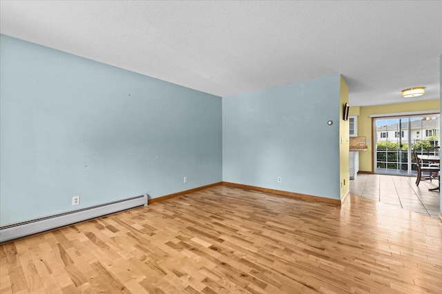 unfurnished living room with a baseboard heating unit, wood finished floors, baseboards, and a textured ceiling