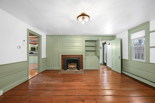 unfurnished living room with a baseboard heating unit, a brick fireplace, and hardwood / wood-style flooring