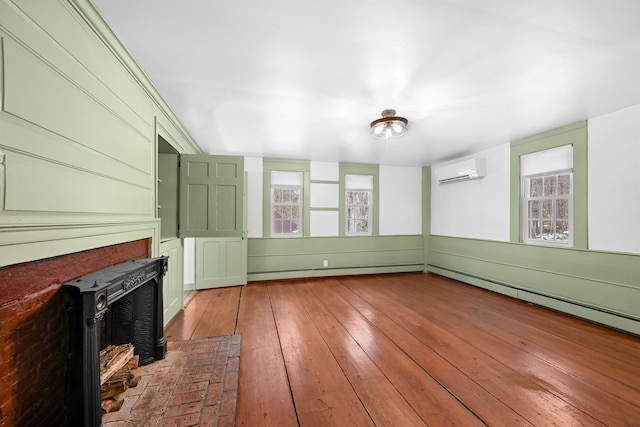 unfurnished living room with a wall mounted air conditioner, a baseboard heating unit, a brick fireplace, and hardwood / wood-style flooring