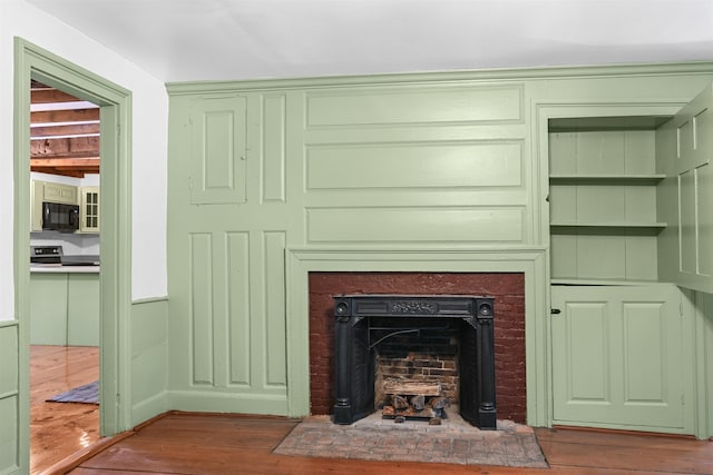 interior details with electric range, a fireplace, black microwave, and wood finished floors