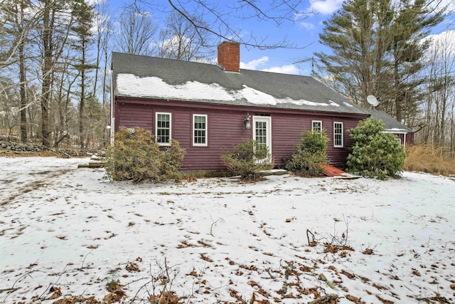 snow covered house featuring a chimney