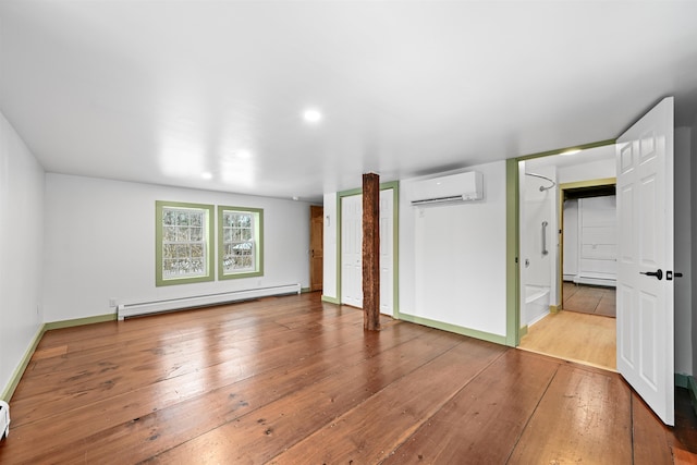 interior space with wood-type flooring, baseboards, baseboard heating, and a wall mounted AC