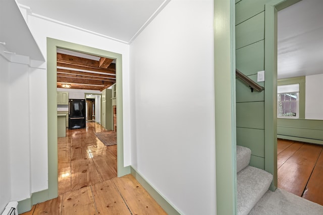 corridor featuring a baseboard radiator, baseboards, light wood-style floors, and stairs