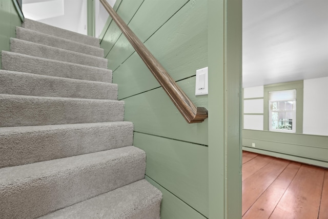 stairs with baseboard heating and hardwood / wood-style floors