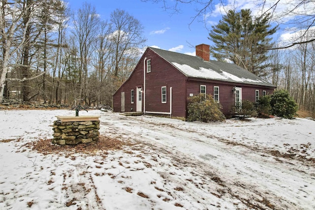 view of snow covered exterior with a chimney