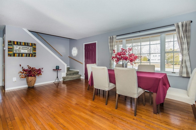 dining room featuring stairs, baseboards, and wood-type flooring