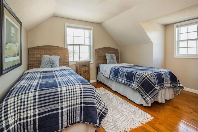 bedroom with a textured ceiling, baseboards, lofted ceiling, and wood finished floors