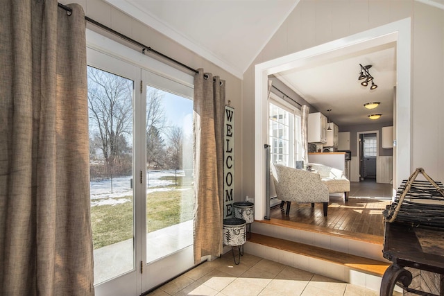 doorway to outside featuring light tile patterned flooring, crown molding, and lofted ceiling