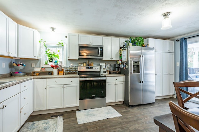 kitchen with dark wood finished floors, visible vents, white cabinets, and appliances with stainless steel finishes